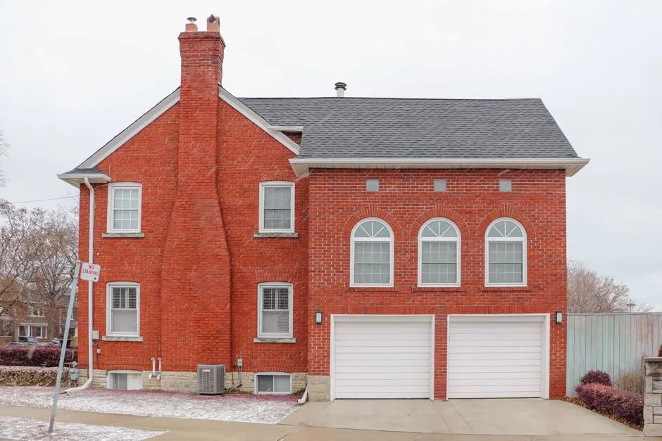 Red brick house exterior in Toronto with arched windows, chimney, and double garage.